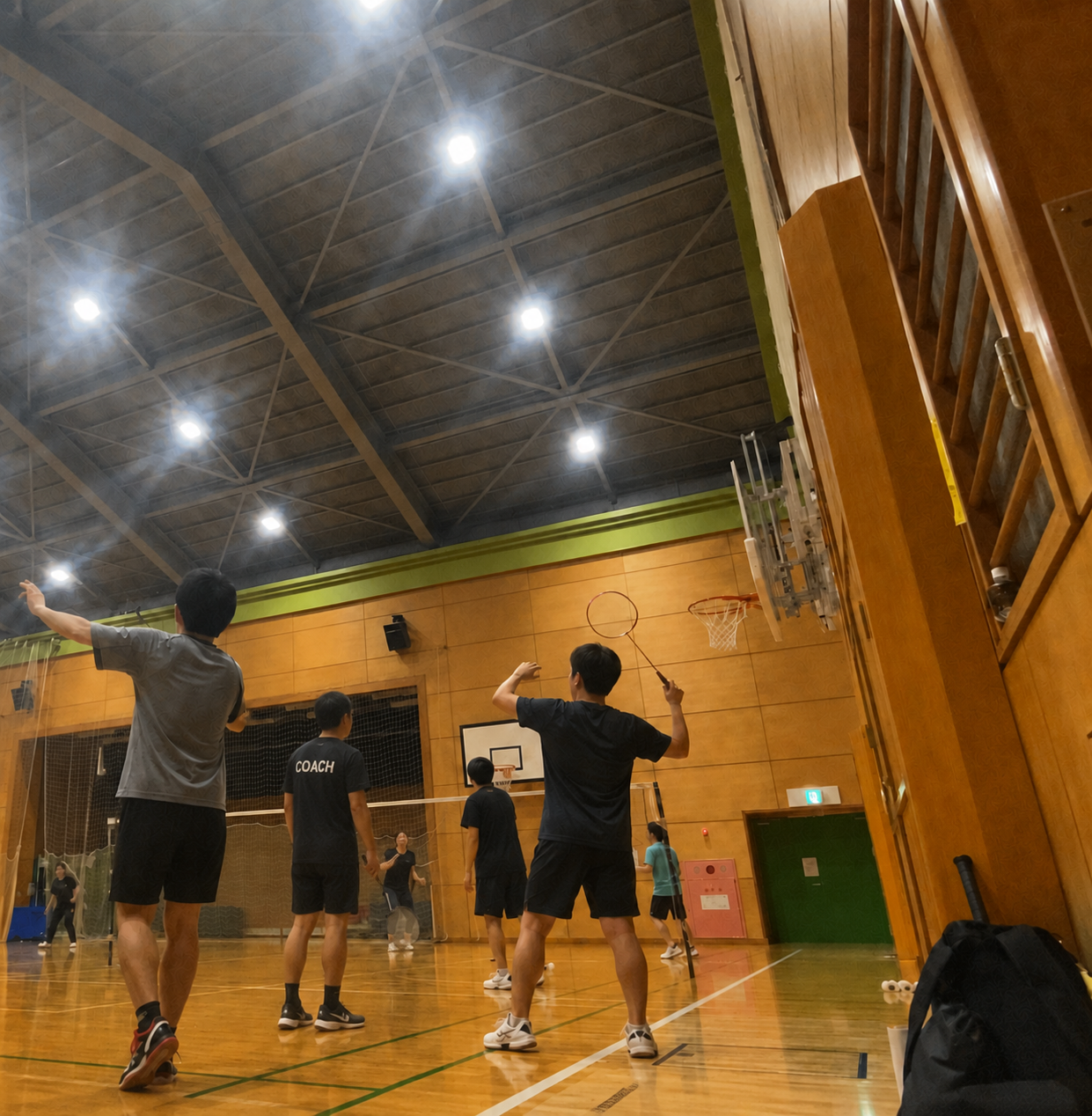 体育館で男性コーチが指導するバドミントン練習風景